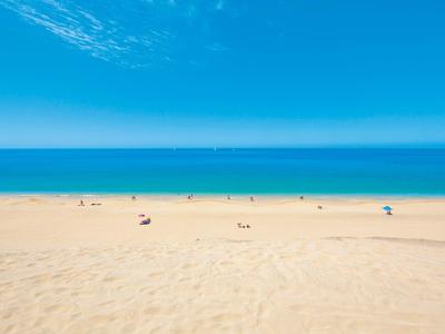 Spiaggia di sabbia fine con cielo azzurro e mare calmo.