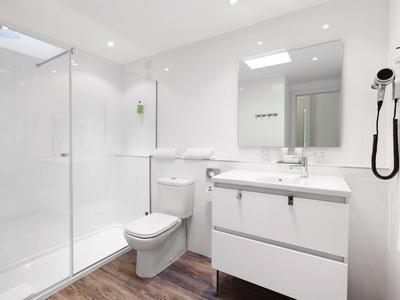 Bagno moderno con doccia in vetro, WC e lavabo bianco, pavimento in legno.