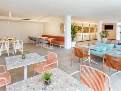 Sala luminosa con tavoli in marmo, sedie moderne e divani per il relax.