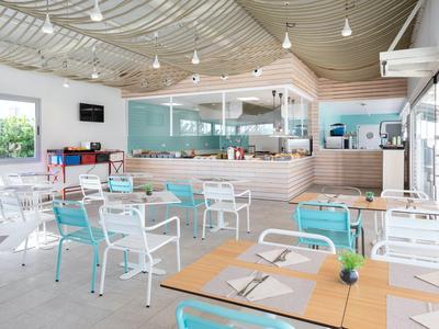 Modern bright restaurant with white and blue chairs and large windows.