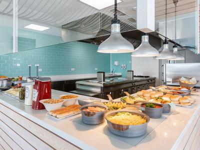 Buffet with various hot and cold dishes in a modern hotel restaurant.