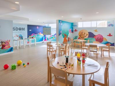 Bright, child-friendly hotel area with tables and colorful toys on the floor.