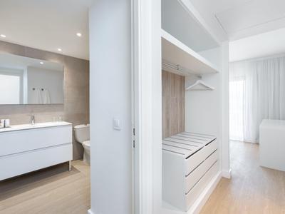 Modern hotel room area with open wardrobe and adjoining bathroom featuring white fixtures.