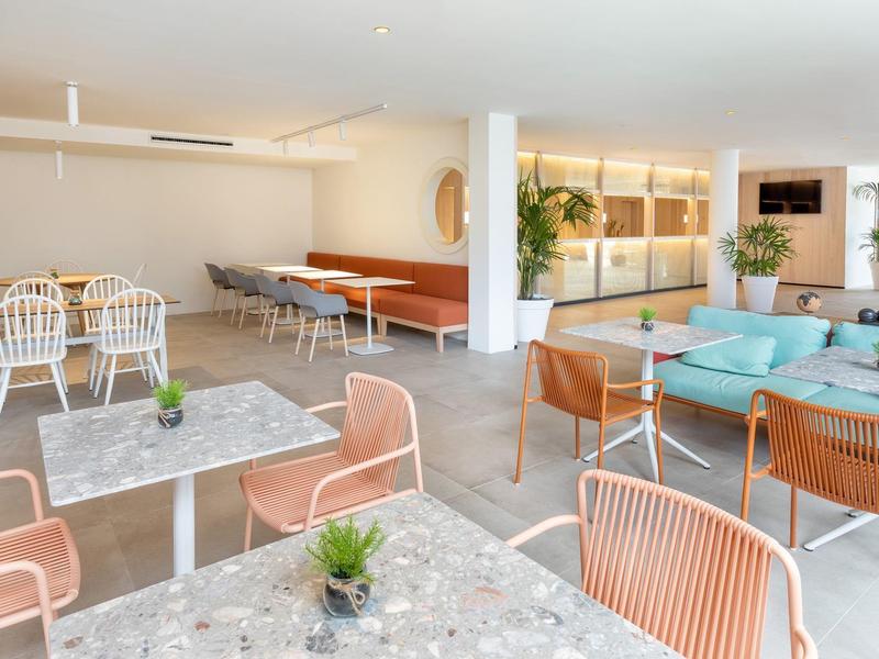 Sala luminosa con tavoli in marmo, sedie moderne e divani per il relax.