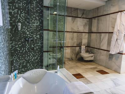 Modernes Badezimmer mit freistehender Badewanne, Glasduschwand und weißen Mosaikfliesen.