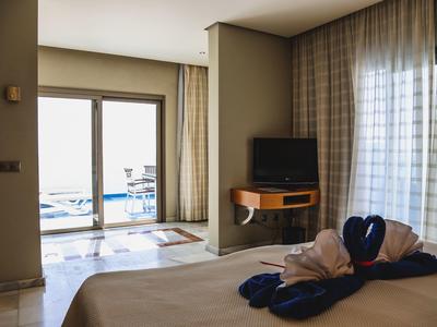 Schlafzimmer mit Doppelbett, dekorativen Handtüchern und Balkon mit Meerblick bei Tageslicht.