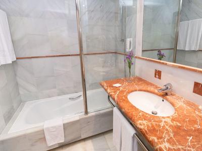 Helles Badezimmer mit Marmorwaschbecken, großem Spiegel und begehbarer Dusche.