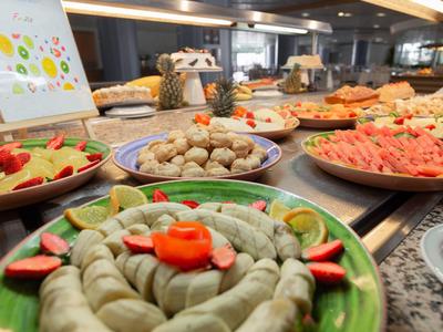 Buffet mit verschiedenen Speisen, darunter gefüllte Blätter, Fleischbällchen und Melone, auf Tellern angerichtet.