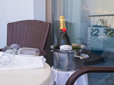 Un tavolo con calici da vino, una bottiglia di champagne in un secchiello con ghiaccio e una sedia su un balcone.