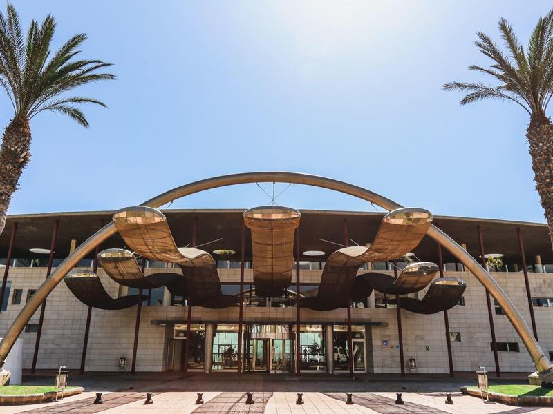 Ingresso moderno dell'hotel con arco in legno curvo e palme