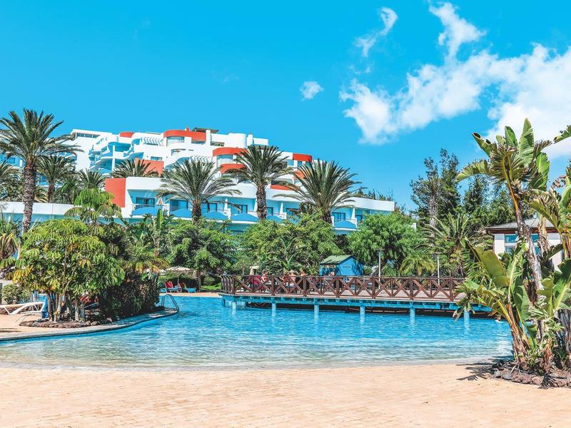 Hotel con piscina e palme sotto un cielo azzurro limpido