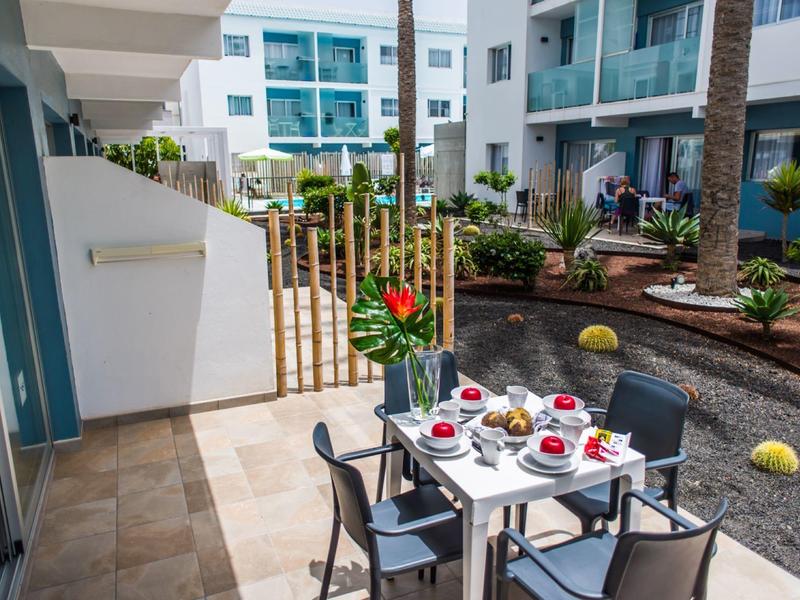 Terrace with set dining table and flower decoration in a modern holiday complex.