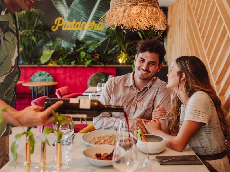 Couple enjoying a relaxed meal with wine in a cozy restaurant.