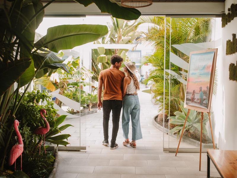 Couple entering a bright tropical hotel lobby with plants