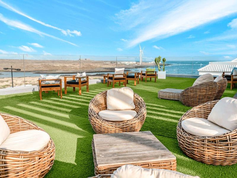 Cozy lounge seating on terrace with sea view and blue sky.