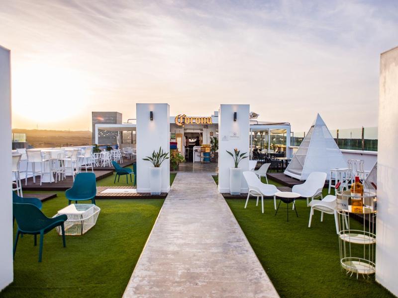 Rooftop terrace with chairs, tables, and umbrellas at sunset.