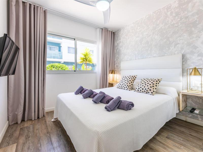 Modern hotel room with double bed, decorative pillows, towels, and window with curtains.