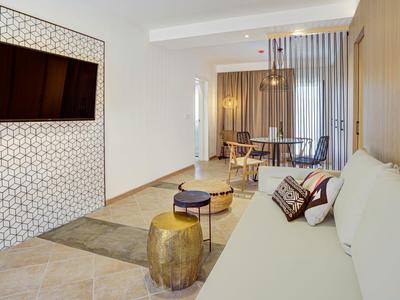 Soggiorno moderno con divano, TV a parete e zona pranzo sullo sfondo.