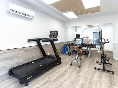 Palestra moderna con tapis roulant, manubri e vari attrezzi per esercizi in una stanza luminosa.