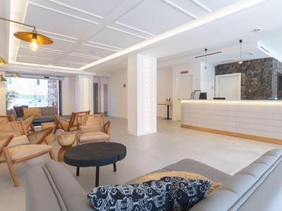 Luminoso atrio dell'hotel con sedie comode, un divano e una reception moderna.