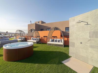 Terrazza dell'hotel con vasca idromassaggio, lettini e doccia esterna sotto un cielo limpido.