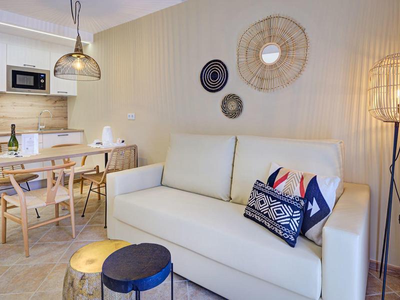 Soggiorno arredato in stile moderno con divano bianco e zona pranzo in toni caldi.