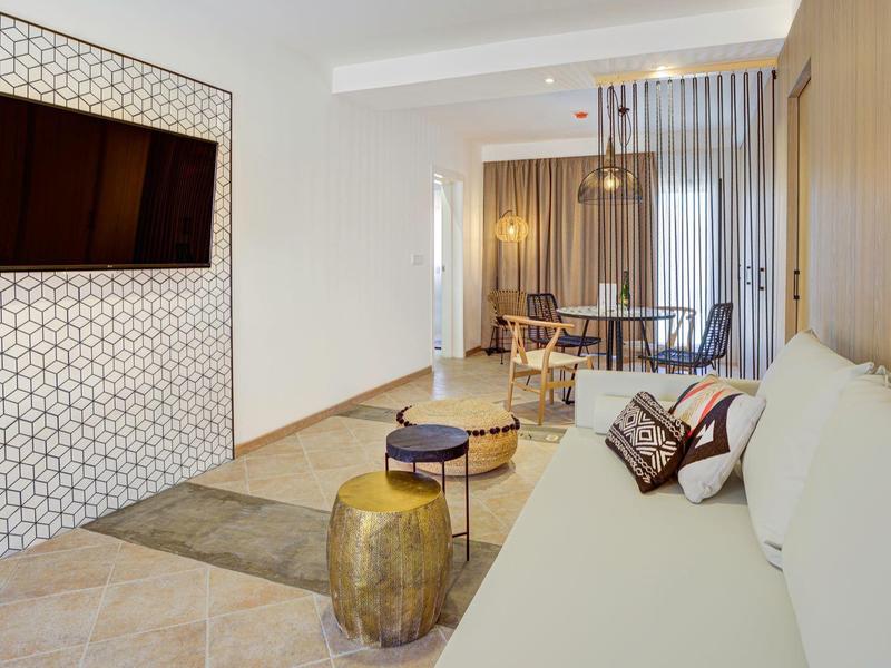 Soggiorno moderno con divano, TV a parete e zona pranzo sullo sfondo.