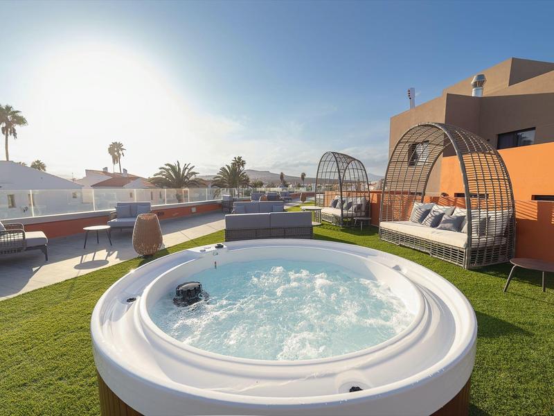 Vasca idromassaggio moderna all'aperto sulla terrazza sul tetto con posti a sedere e vista sulla città.