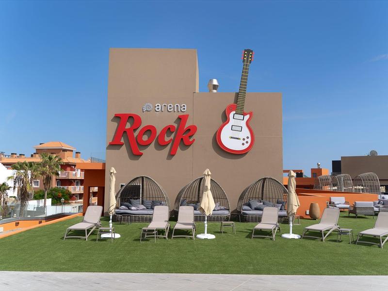 Edificio dell'hotel con scritta rossa 'Rock' e chitarra elettrica, sdraio e ombrelloni davanti.