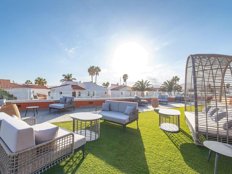 Terrazza sul tetto con mobili da giardino e cesto solare sotto un cielo sereno.