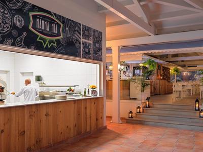 Entrée d'hôtel moderne avec comptoir en bois et four à pain décoratif, éclairée chaleureusement.