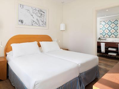 Chambre d'hôtel lumineuse avec deux lits simples et œuvre d'art abstraite au mur.