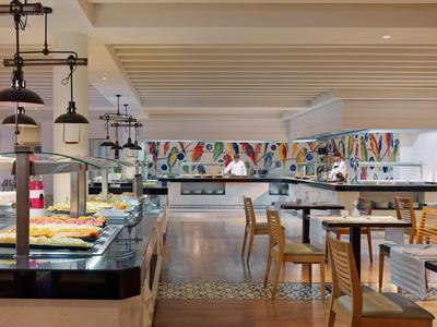 Restaurant d'hôtel moderne avec buffet et décorations murales colorées.