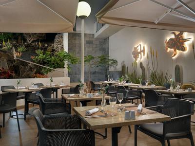 Espace extérieur d'hôtel convivial avec tables dressées et éclairage moderne.