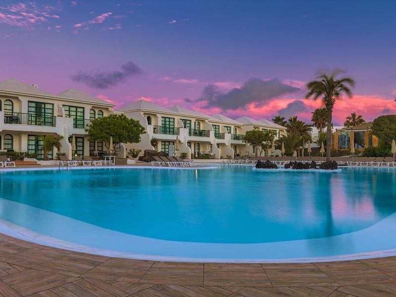 Hotel pool at sunset with palm trees and two-story buildings in the background