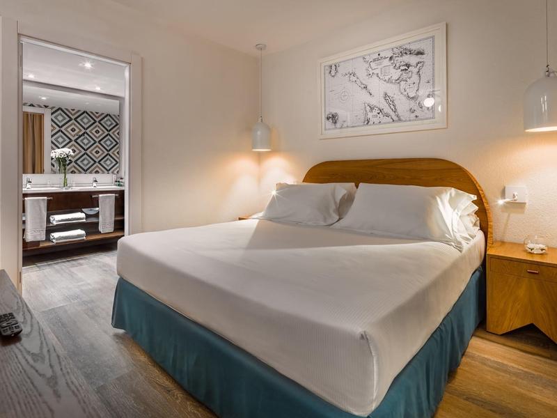 Cozy hotel room with a large bed, wooden furniture, and an ensuite bathroom.