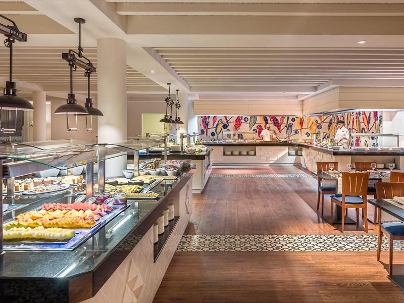 Spacious hotel buffet area with well-lit dessert and food displays and seating arrangements.