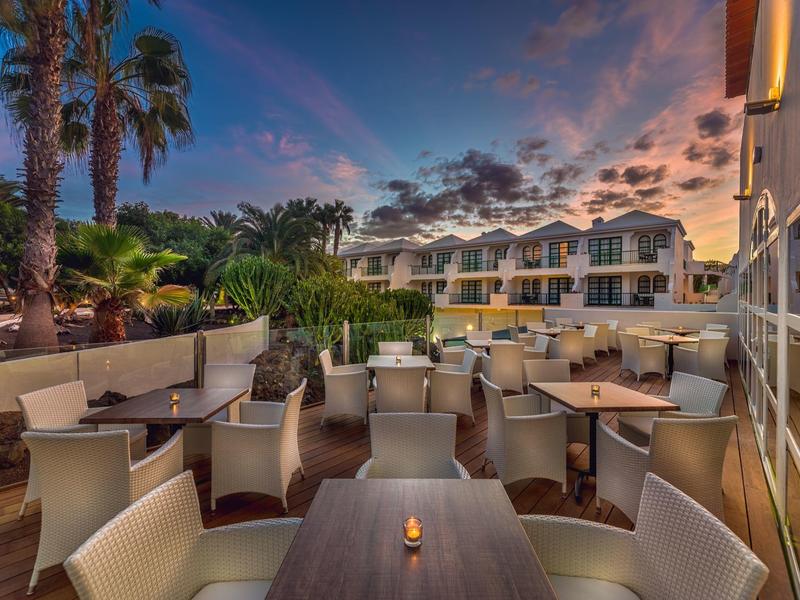 Outdoor hotel terrace with empty tables and cozy candlelight at sunset.