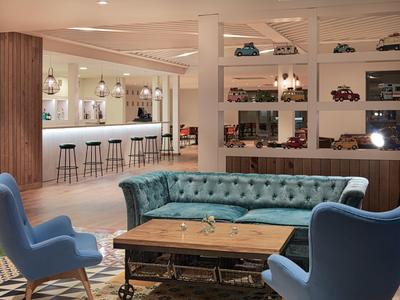 Modern hotel lounge area with blue armchairs, green sofa, and wooden tables.