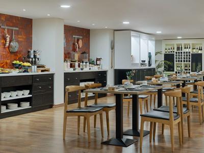 Modern dining area with wooden tables and chairs, warmly lit and elegantly arranged.
