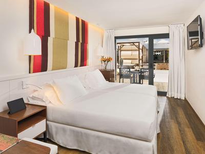Modern hotel room with double bed, colorful wall decor, and access to a terrace.