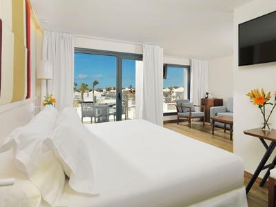 Bright hotel room with large bed and city view from balcony.