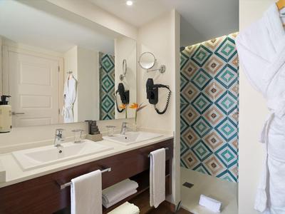 Modern bathroom area with double sinks and colorful shower in a hotel.