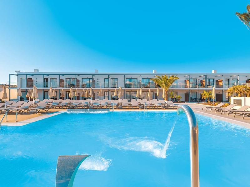 Outdoor pool with lounge chairs under clear blue sky at a modern hotel.