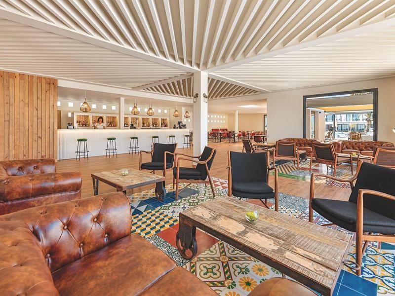 Stylish lounge area with patterned floor tiles, leather chairs, and a white bar in the background.