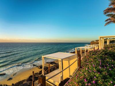 Spiaggia con aree salotto e vista sul mare sotto un cielo sereno al tramonto