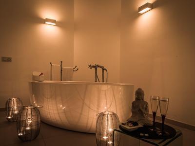 Elegante vasca da bagno con illuminazione soffusa e accessori decorativi in una stanza rilassante.