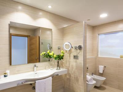 Bagno moderno con grande specchio, lavabo doppio e composizione floreale.