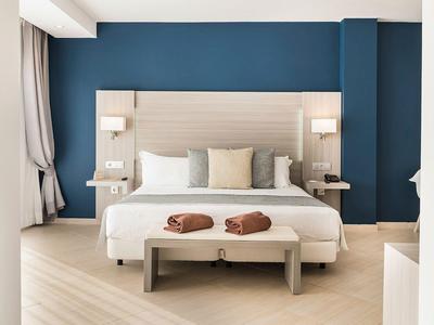 Camera d'hotel moderna con letto grande, due asciugamani e parete accentuata blu.