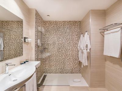 Bagno luminoso con doppi lavandini e doccia a pioggia con parete a mosaico.